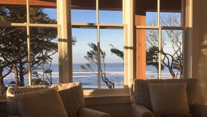Una stanza con un'ampia finestra vista mare, due poltrone a fantasia e un soffitto in legno.