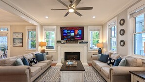 Ein Wohnzimmer mit zwei Sofas, einem Kamin, einem Flachbildfernseher und einem Deckenventilator.