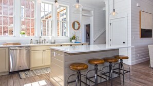 Una cocina moderna con una isla grande, taburetes de bar e iluminación colgante.