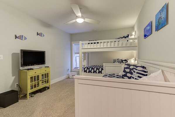 A bedroom with bunk beds, a television on a cabinet, and artwork on the walls. - Seabrook Madison House | Town Center, Sleeps 12 | 4BR, Full Kitchen, BBQ Balcony (Pacific Beach)