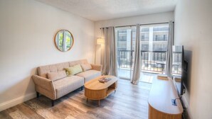 A modern living room with a sofa, a coffee table, and a TV. - 2 bedroom apt near beach w/pool (Sunny Isles Beach)