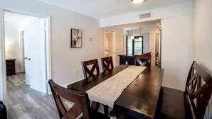 A dining area with a long table, six wooden chairs, and a rug. - 2 bedroom apt near beach w/pool (Sunny Isles Beach)