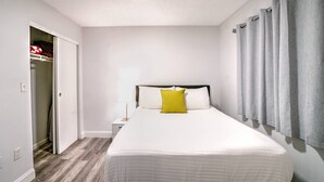 A bedroom with a bed, a nightstand, a lamp, a closet, and a window with curtains. - 2 bedroom apt near beach w/pool (Sunny Isles Beach)