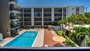 A hotel with a swimming pool, sun loungers, and palm trees. - 2 bedroom apt near beach w/pool (Sunny Isles Beach)