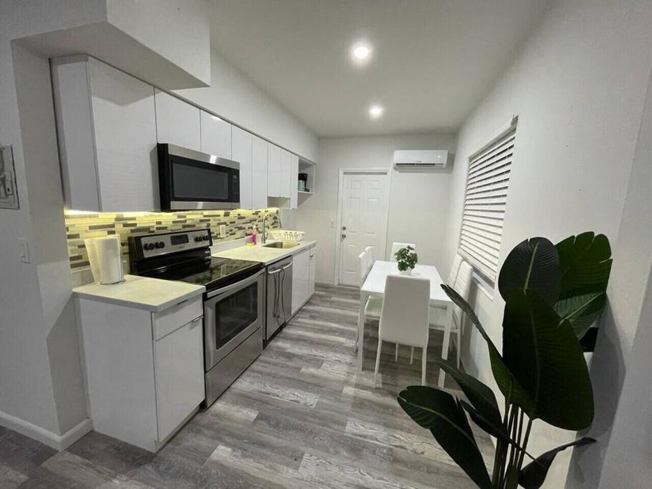 A compact kitchen with white cabinets, a microwave, and a dining area with a table and chairs.