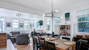 A spacious living room with a dining area, large windows, and a television mounted on the wall. - Seabrook Oceanview Home | Dog Friendly | Hot Tub, Pool & Gym | Sleeps 12 (Pacific Beach)
