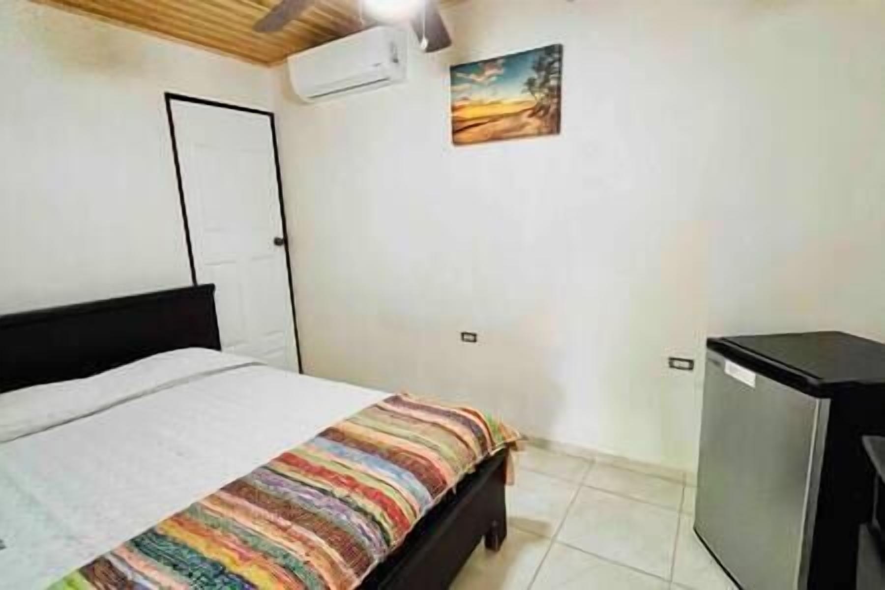 Une chambre à coucher comprenant un lit, un bureau et un climatiseur fixé au mur.