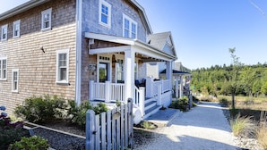 A two-story wooden house with a porch, a gravel driveway, and a fenced yard. - Seabrook's Ocean's Roar from this beautiful, dog-friendly home! (Pacific Beach)