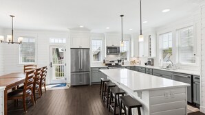 A modern kitchen with white cabinetry, stainless steel appliances, and a large island with bar stools. - Seabrook's Ocean's Roar from this beautiful, dog-friendly home! (Pacific Beach)