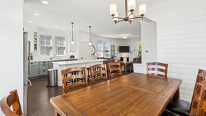 A modern kitchen with white cabinetry, a wooden dining table, and a chandelier. - Seabrook's Ocean's Roar from this beautiful, dog-friendly home! (Pacific Beach)