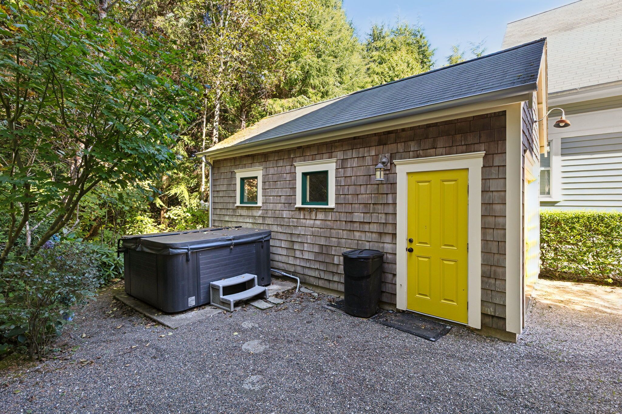 Un petit bâtiment d’un seul étage, avec une porte jaune et un grand jacuzzi noir à l’avant.