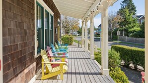 Una terraza de madera con sillas Adirondack de colores y un porche cubierto.