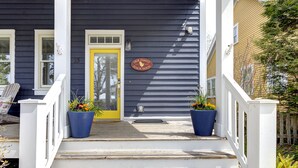 A house with a porch, a yellow door, and a sign that reads "Our Family Beach House." - Seabrook Family Beach Home | Pet Friendly, Hot Tub | 3BR, Crescent Park (Pacific Beach)