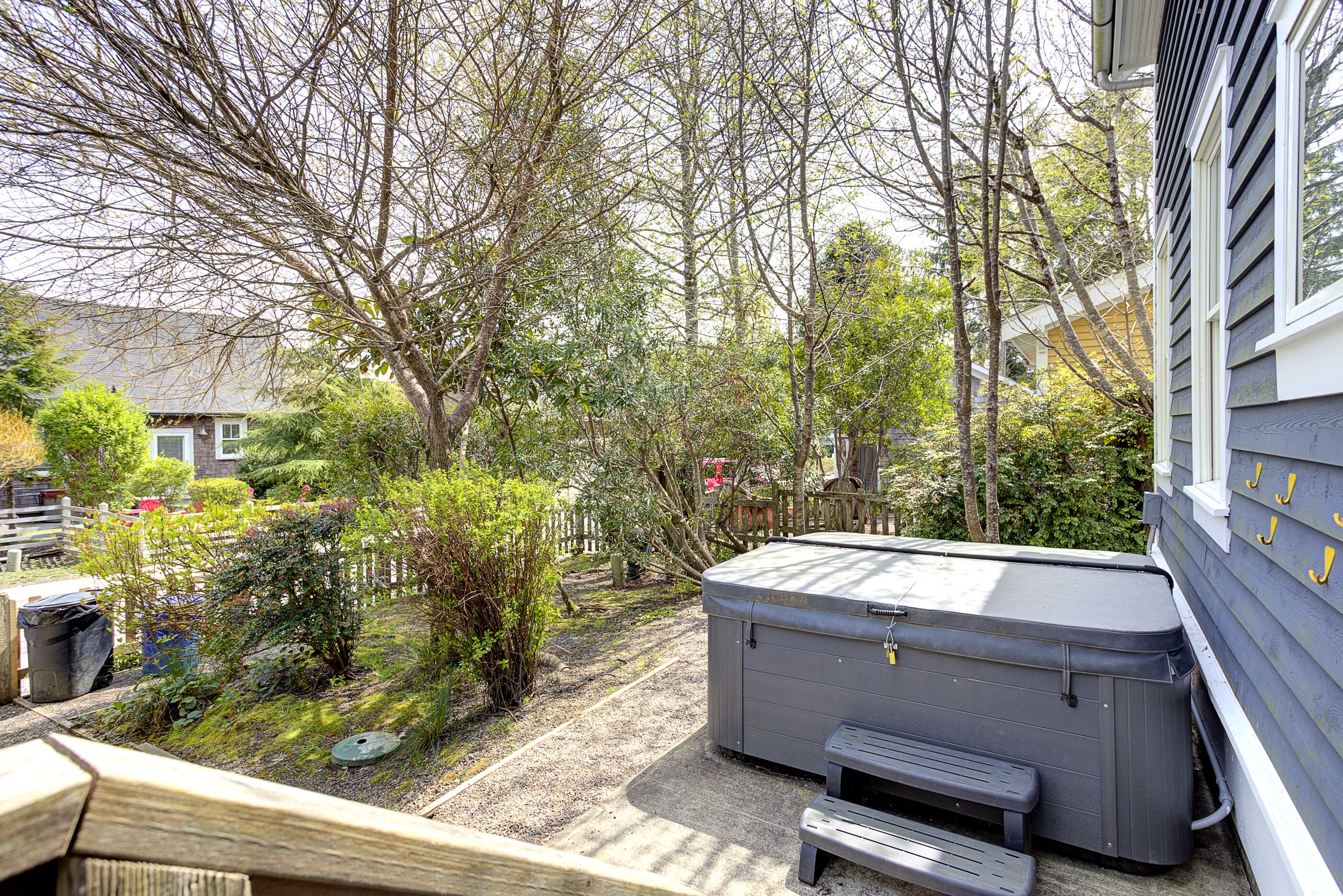 Een achtertuin met een jacuzzi, een houten bank en een houten terras.