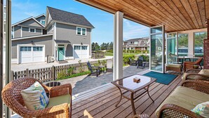 Eine überdachte Terrasse im Freien mit Korbmöbeln und einer Glastür, die in einen Garten führt.