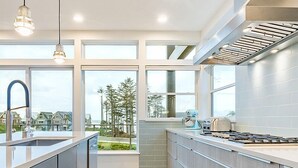 Uma cozinha moderna com ilha central, eletrodomésticos de aço inoxidável e janelas amplas com vista para o exterior.