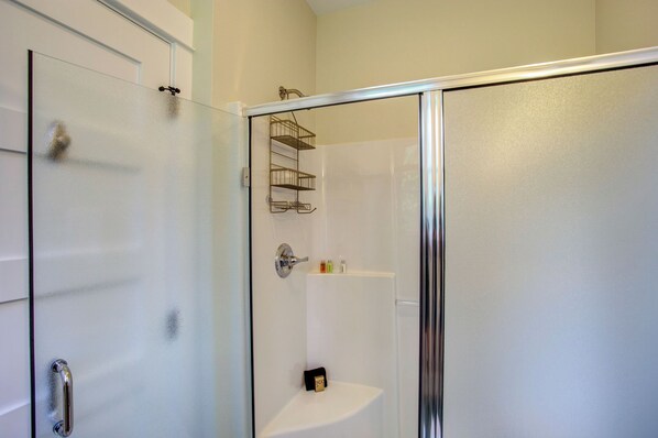 A modern bathroom with a glass shower enclosure, a white sink, and a metal towel rack.