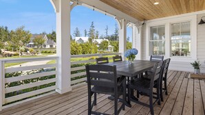 A covered patio with a wooden table and chairs, white railings, and a view of houses and trees. - *NEW* Sand by Me, a beautifully furnished farmhouse! (Pacific Beach)