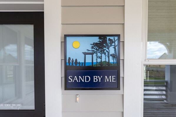 A sign with a landscape scene and the text "SAND BY ME".