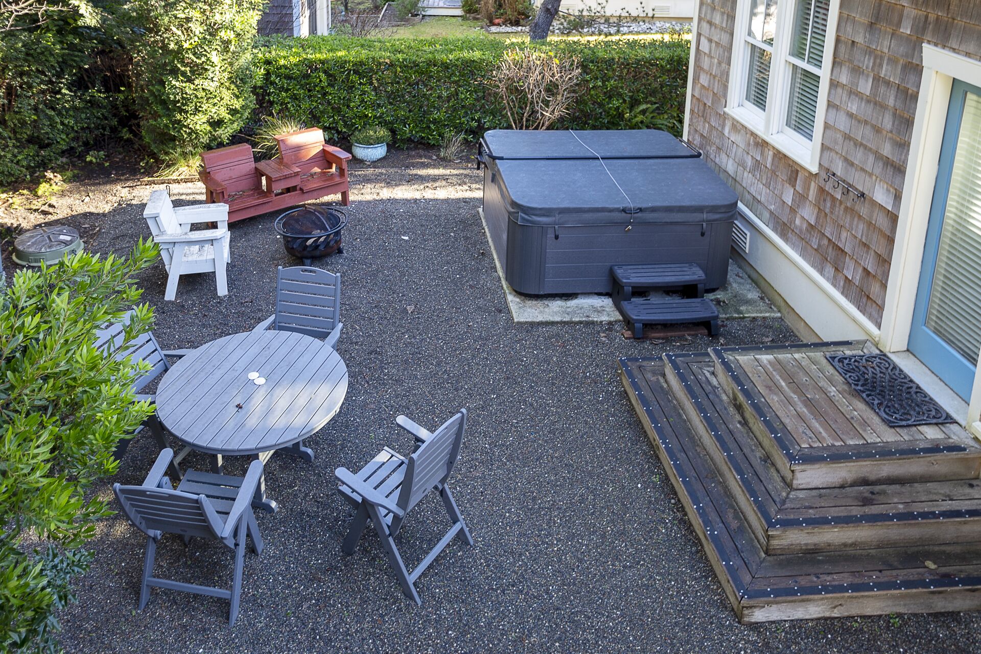 Een terras met een ronde tafel en stoelen, een vuurkuil en een grote terrasverwarmer.
