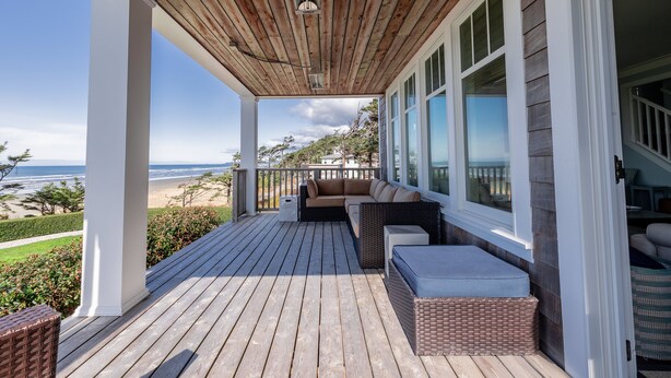 A wooden deck with a sofa and cushions, overlooking a beach. - Seabrook Sandy Side Up | Oceanfront, Hot Tub | 4BR, Sleeps 10, Seastack Views (Pacific Beach)