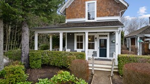 A two-story house with a porch, white exterior, and a number 33 sign.
