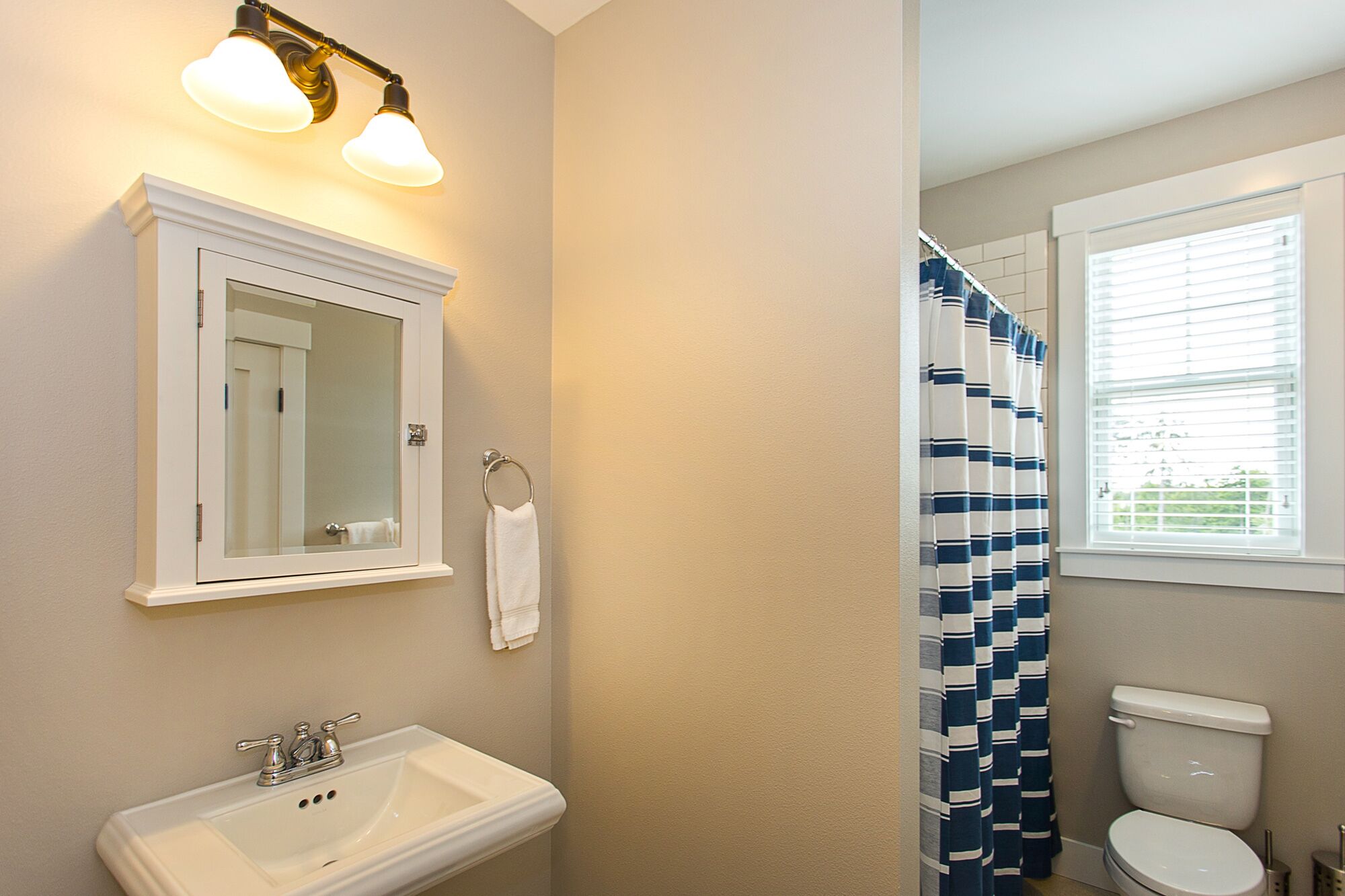 A bathroom with a white sink, a mirror, a towel ring, and a shower curtain.