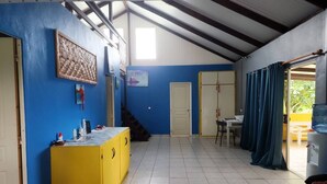 Une pièce avec un meuble jaune, un bureau, une chaise et un lit. Un escalier mène à une autre pièce.