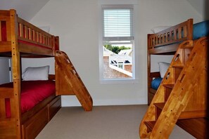 Ett rum med två våningssängar, ett fönster och utsikt över ett hus utanför.
