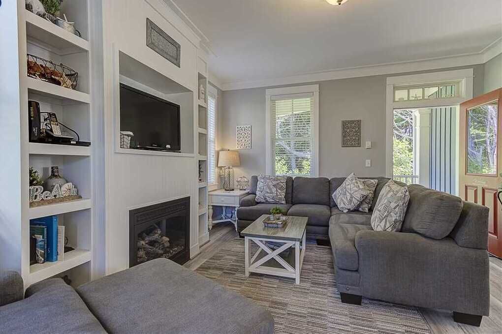 A living room with a fireplace, a grey sofa, a coffee table, and a bookshelf.