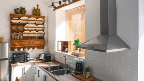 Een keuken met een ingebouwde kookplaat, een spoelbak en een raam met zonwering.