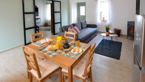 Een eethoek met een houten tafel en stoelen, een bank en een kleine tafel met een plant in pot.