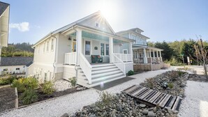 A two-story house with a covered porch, a front staircase, and a gravel driveway. - Seabrook Somewhere in Time | Themed Rooms, Hot Tub | 4BR, Sleeps 11, South Farm (Pacific Beach)