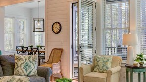 A living room with a sofa, armchair, and a coffee table. There is a dining table with chairs and a clock on the wall. - Seabrook Spindrift | Ocean Views, Beach Access, 4BR, Sleeps 10 (Pacific Beach)