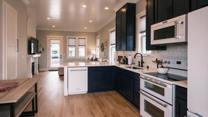 Una cocina moderna con armarios oscuros, electrodomésticos blancos y piso de madera.