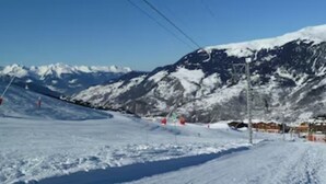 A snowy ski slope with a clear sky and mountains in the background. - Ski in/out Studio, sleeps 2/3 (Courchevel)