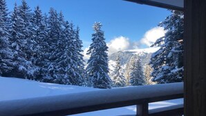 A snowy mountain landscape with a wooden balcony railing. - Ski in/out Studio, sleeps 2/3 (Courchevel)