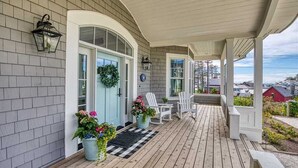 A covered porch with a checkered mat, white chairs, and potted plants. - Seabrook Sunset Retreat | Pet Friendly, Ocean View | 6BR, Sleeps 15, Sauna (Pacific Beach)