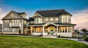 A two-story house with a front porch, a garage, and a well-maintained lawn. - Seabrook Sunset Retreat | Pet Friendly, Ocean View | 6BR, Sleeps 15, Sauna (Pacific Beach)