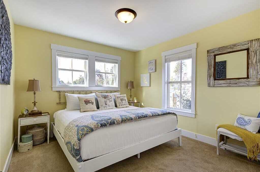 A bedroom with a bed, two bedside tables, a window, and a mirror.