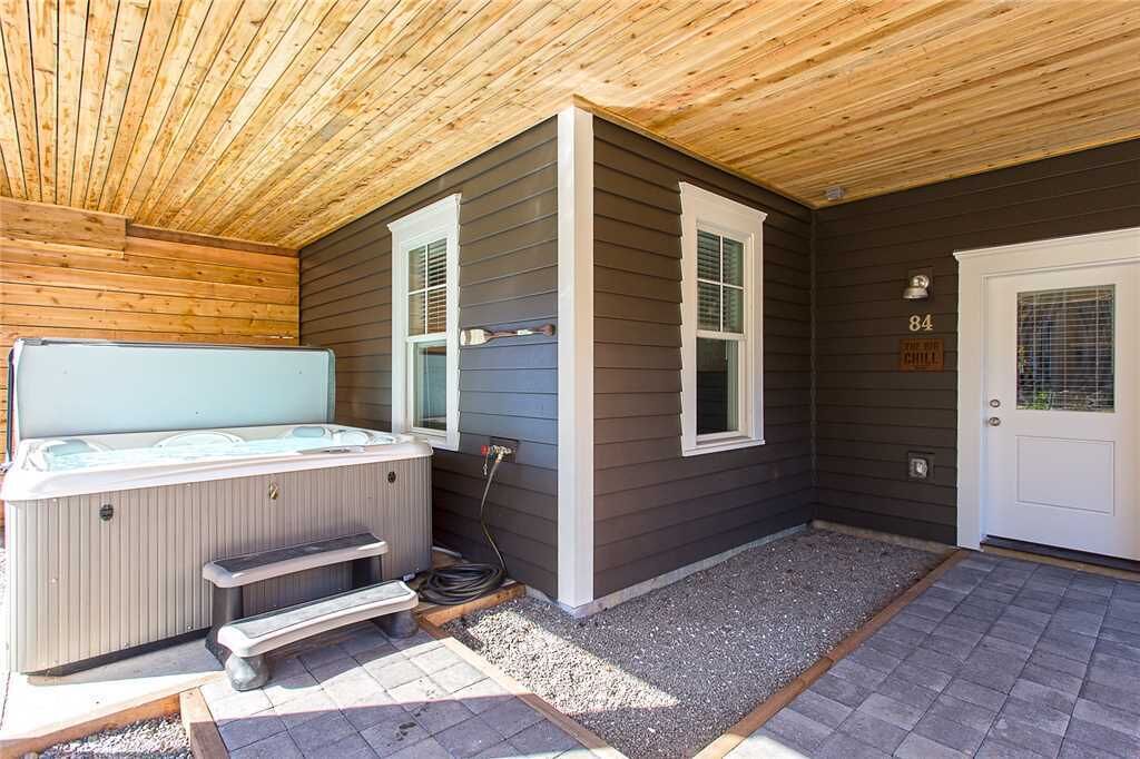 A covered outdoor area with a hot tub, a door labeled "84", and a small bench.