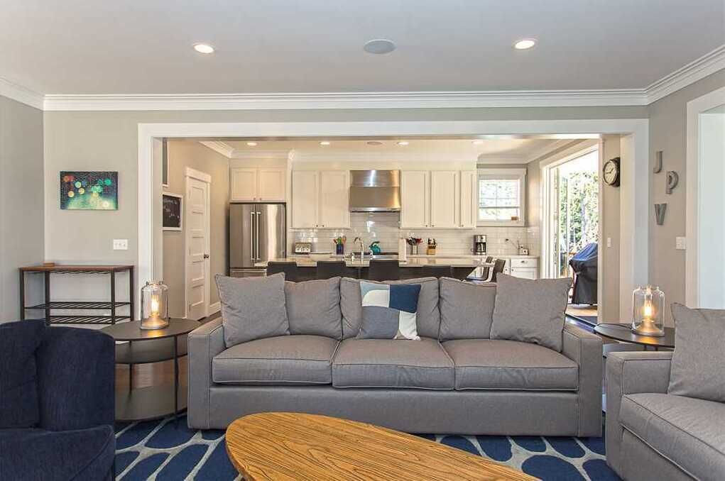 A modern living room with a grey sofa, a wooden coffee table, and a small side table with a lamp.