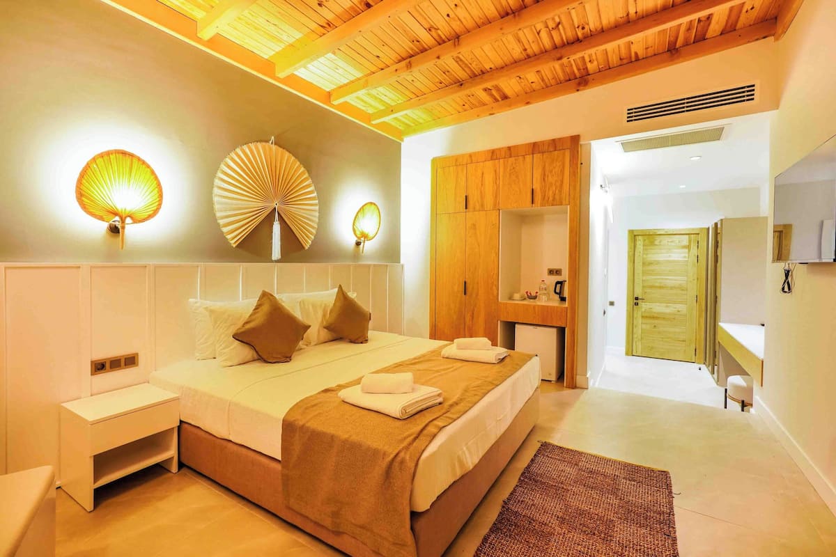 A bedroom with a bed, bedside tables, a wooden ceiling, and a mirror.