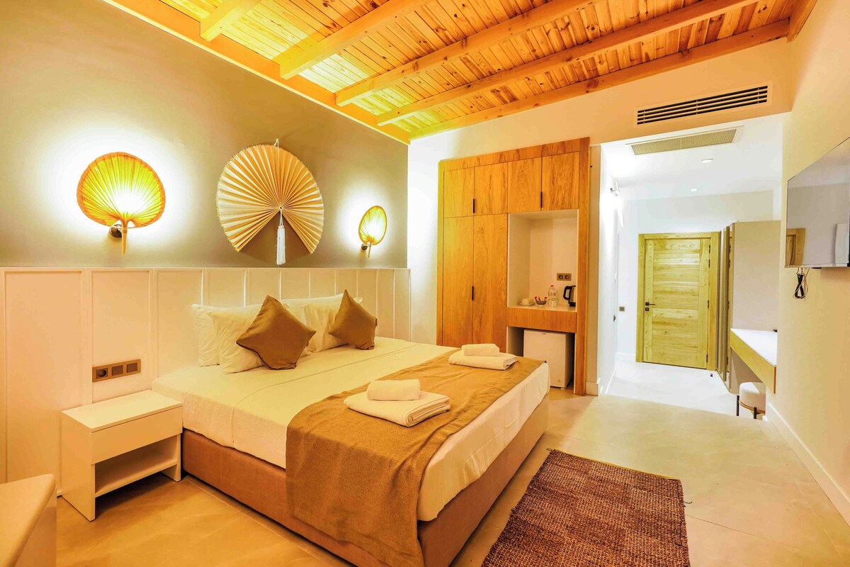 A bedroom with a bed, bedside tables, a wooden ceiling, and a mirror.