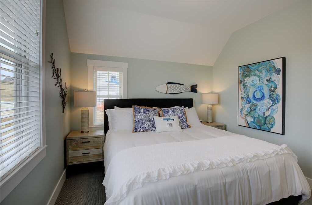 A bedroom with a bed, nightstands, a wall art piece, and a window with blinds.