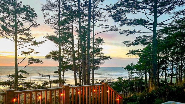 A wooden deck with a hot tub and a bench overlooking the ocean.