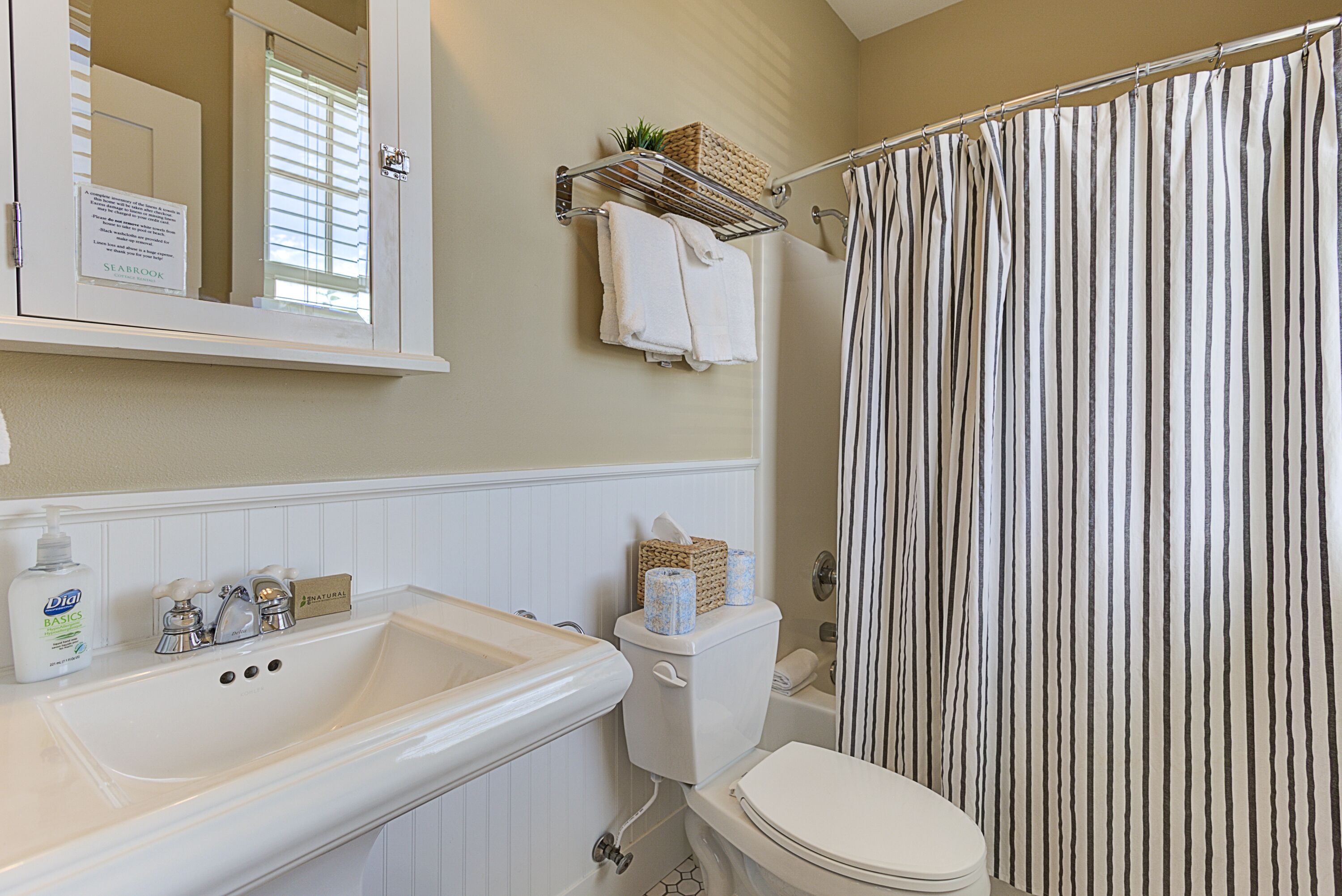 A bathroom with a white sink, a toilet, a shower curtain, and a mirror.