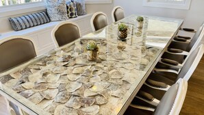 A dining table with a glass top and a shell pattern, surrounded by chairs with a beige and brown color scheme. - *New* Seabrook's Togadera: Luxury ocean front home! (Pacific Beach)