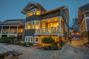 A multi-story house with a balcony, a driveway, and a small garden area.