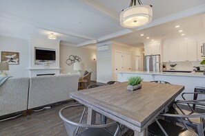 Een moderne keuken met witte kasten, een roestvrijstalen koelkast en een eethoek met een houten tafel en metalen stoelen.